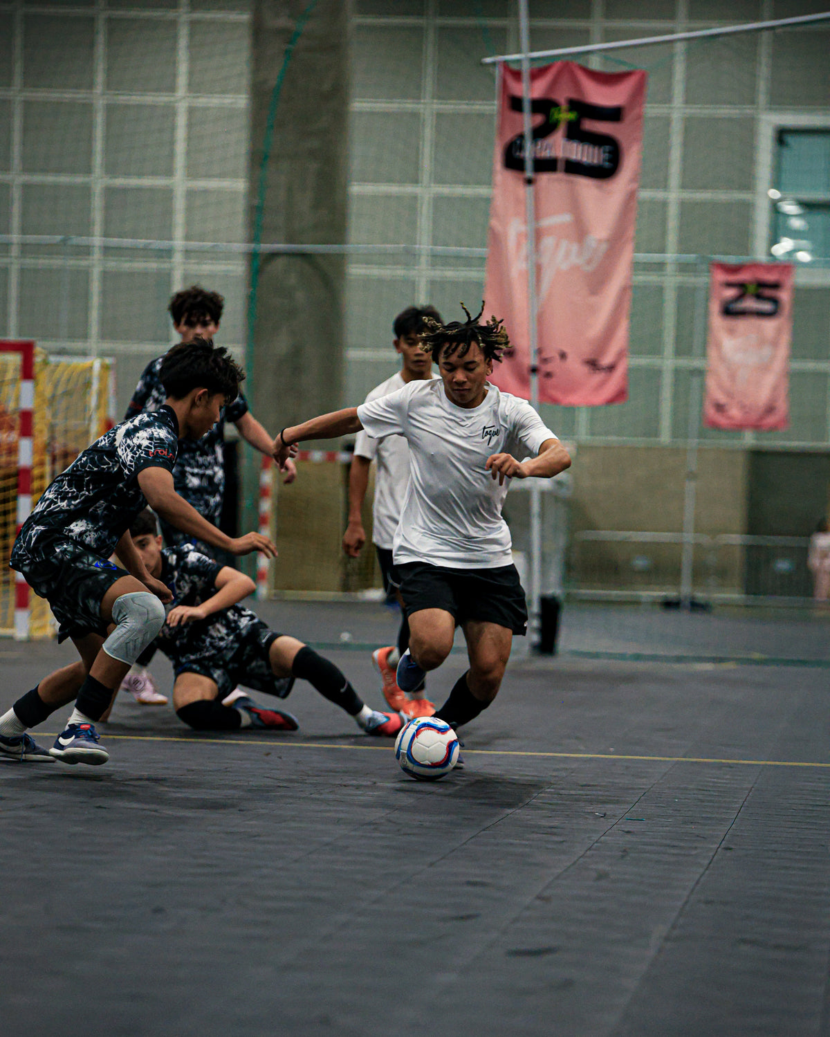 Group of young people playing soccer indoors with banners in the background
