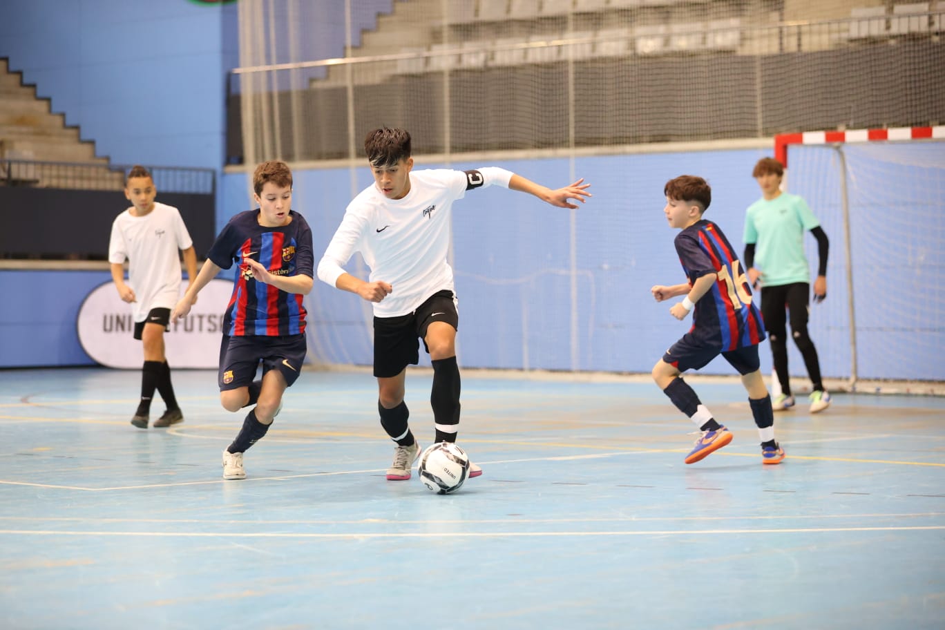 Children playing indoor soccer with a blue wall and goal in the background